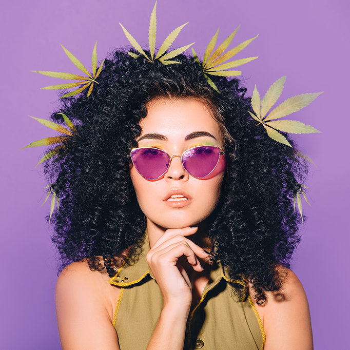 Hipster Lady wearing sunglasses with cannabis leaves in her hair