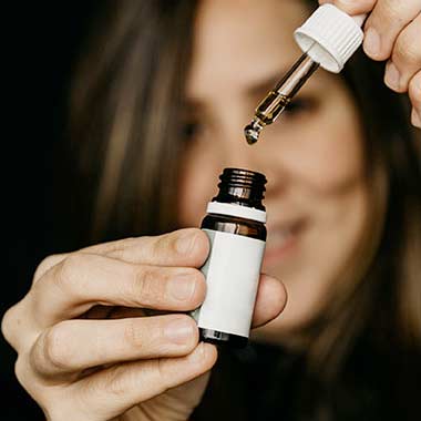 women holding a cannabis tincture with a dropper and bottle