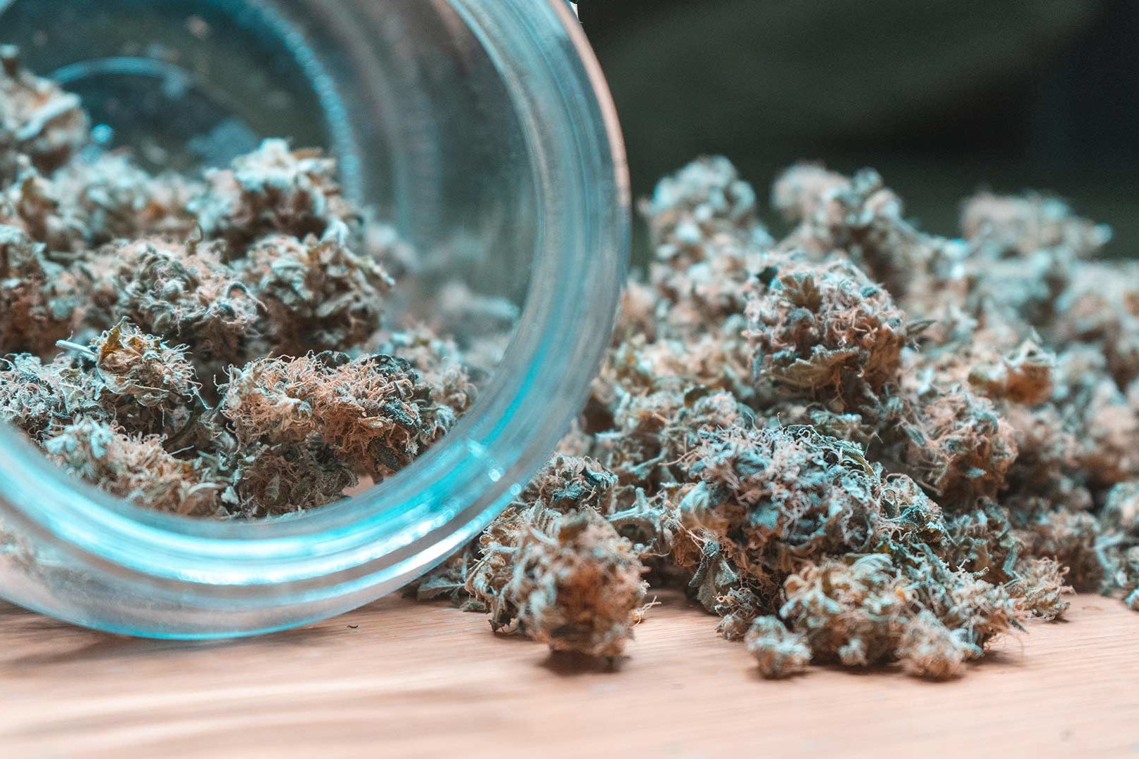 cannabis flower spilling out a glass jar on it's side