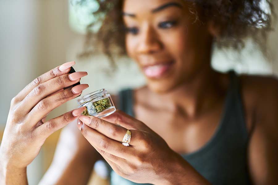 Smiling woman holding a glass jar of weed