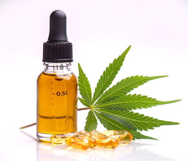 CBD Hemp Oil in a Tincture next to Oil in capsules and a hemp leaf