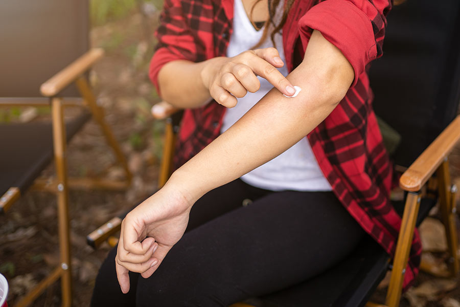Women in flannel short applying THC Lotion to forearm